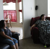 Olivia sits in her brother's living room after her daily exercise. In addition to walking around the neighborhood, she must go up and down a flight of stairs each time she enters and leaves the guest bedroom.