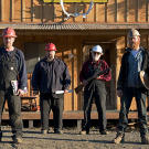 The miners take their stand in front of their Porcupine Creek headquarters, built shortly after they first took possession of their claim. As a tribute to the first generation of miners who came to Porcupine Creek in the late 1890's, the 21st century crew put up a sign offering the going rate for coffee and a bath over century ago.