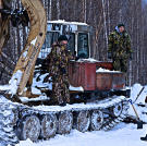 The team trying to fix the skidder. Cold weather can wreak havoc on engines, stress metal and other equipment parts, and kill machine batteries.
