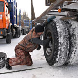 The driver works on the wheels of a log trailer.