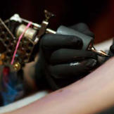 Kat creates the tattoo, using a machine designed by Samuel O’Reilly in the late 1800s and modeled after Thomas Edison’s autographic printing pen. It creates the tattoo through quick, repeated punctures into the skin, where ink is deposited.