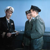 Commander Noorfleet (left) accepts the formal surrender of U-858 from her CO, Kapitänleutnant Thilo Bode (right) aboard ATR-57. The German u boat was the first to surrender in U.S. waters. LT Robert H. Braun (center) served as translator 14 May 1945. Noticed Bode's specially-treated leather pants.
