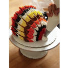 When you've finished feathering your frosting, use white buttercream to create the turkey's beak. Pull up and out from the bottom front of the cake to make the beak.