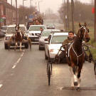 Gypsy men on horses share a highway with cars.
