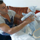Women are the typical caretakers, but this gypsy tries his hand at swaddling a baby.