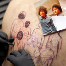Tommy Montoya tattooing a Hawaiian portrait on Carson's back.