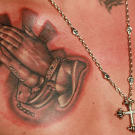 Close up of the praying hands tattoo.