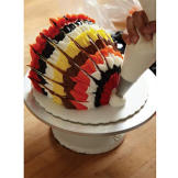 When you've finished feathering your frosting, use white buttercream to create the turkey's beak. Pull up and out from the bottom front of the cake to make the beak.
