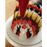 Using the red buttercream, pipe a comb on top of the turkey's head.
