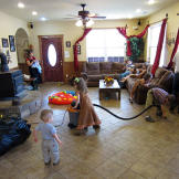 The little Bates kids help vacuum the living room.