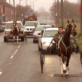 Gypsy men on horses share a highway with cars.