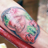 Megan Massacre finishes a Santa tattoo on Frank's arm.