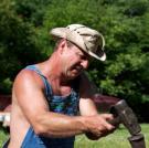 Tim uses a sledgehammer to drive a wedge between the tire and rim.