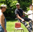 Tickle climbs into a construction harness while Tim and JT check out the framing on their new still house.