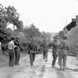 Battle Group Commander Major D.V. Currie at left supervises the round up of German prisoners at St. Lambert-sur-Dive, France, August 19, 1944. This photo captures the very moment and actions that led to Major Currie being awarded the Victoria Cross, the highest award given to military members of Commonwealth countries.