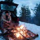 Les Stroud warms by a fire in the Norwegian mountains.