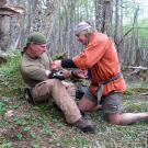 Cody uses moss and wilderness medical skills to dress Dave's wound that was first cauterized with a black powder burn.