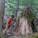 Cody puts the finishing touches on an elaborate "wiki-up" shelter. Cody has built hundreds of such structures including ones he used as a home during his college days.