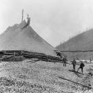 Miners stand next to a massive tailings pile in the heart of the Klondike gold fields. Moving and disposing of massive spoil piles demanded considerable time and labor.