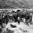 A group of miners employed by one of the Klondike's major claim holders pose with a young girl and a dog. Several years after the beginning of the gold rush, thousands of small claims were consolidated into fewer larger claims that could marshal the resources for mass processing and have some hope of turning a profit.