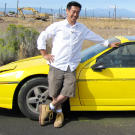 Grant Imahara poses with the remote-controlled car he built to test whether a speeding vehicle can truly skip across a water's surface, as seen in