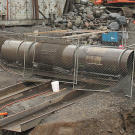 After passing out of the shaker, the sediment moves down a riffled trough lined with "miners moss" that serves as a sluice box to trap nuggets and some of the fine gold. Next, the sediment passes into this ingeniously constructed "trommel", with a rotating drum to wash gold-bearing dirt off rocks. Two sections on the side of the trommel (over the twin troughs) have screen arrays that only allow sand-sized and smaller sediment to pass on down the line. The now concentrated pay dirt moves down a pair of troughs outfitted with sluice boxes for even more recovery.
