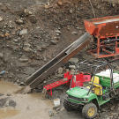 In the final mass-processing step, the pay dirt goes through another round of separation in the Wash Pit. Here a pair of jigs complete the mechanical sorting by extracting the heavier sand-sized fraction for further manual processing. This end product now consists almost exclusively of black sand with variable amounts of fine gold that is loaded into buckets and driven up to the processing tent.