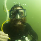 Ian holds a picker — a gold nugget large enough to be picked up by fingers — between his teeth.