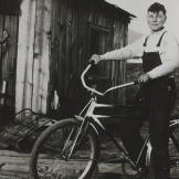 John shows off the bike he bought in 1933 with his earnings from delivering newspapers. John also made money selling used bottles to bootleggers. He collected the bottles in the alleys of Klamath Falls (an early recycler!) and sold them for a penny apiece. Sometimes he could make as much as 15 cents a day!
