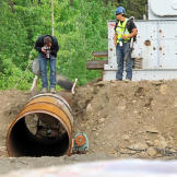 Photographer Paul Kirsop gets a close-up of the newly installed trommel while Safety Supervisor Pattrick Price keeps an eye out for bears. About the only support that the production crew provided for the miners was to team up on security measures to keep everyone safe.