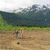 Safety Supervisor Pattrick Price has a conference with miner Safety Officer Jim Thurber about coordinating resources for bear patrols and other safety priorities. These included marking off dangerous terrain and making sure that the film crews stayed clear of equipment hazards.
