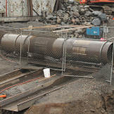 After passing out of the shaker, the sediment moves down a riffled trough lined with "miners moss" that serves as a sluice box to trap nuggets and some of the fine gold. Next, the sediment passes into this ingeniously constructed "trommel", with a rotating drum to wash gold-bearing dirt off rocks. Two sections on the side of the trommel (over the twin troughs) have screen arrays that only allow sand-sized and smaller sediment to pass on down the line. The now concentrated pay dirt moves down a pair of troughs outfitted with sluice boxes for even more recovery.