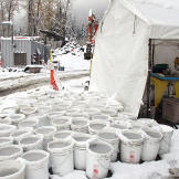 Buckets of "pay dirt" — topped off with icy slush after a freeze — await final refinement outside the processing tent that contains wave tables, pans and a variety of experimental machines all designed to separate black sand from gold. In a final pass at recovering as much gold as possible, the remaining dirt is all manually panned.