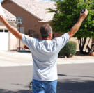 Ed Rosenberg raises his arms in triumph after winning a house.