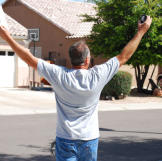 Ed Rosenberg raises his arms in triumph after winning a house.