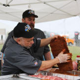 Glenn Gross applies rub to the meat while Edward watches.