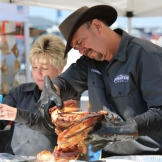 Tommy Houston checks cooked meat while Lisa sauces.